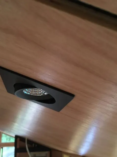 Square black downlight set into a timber ceiling